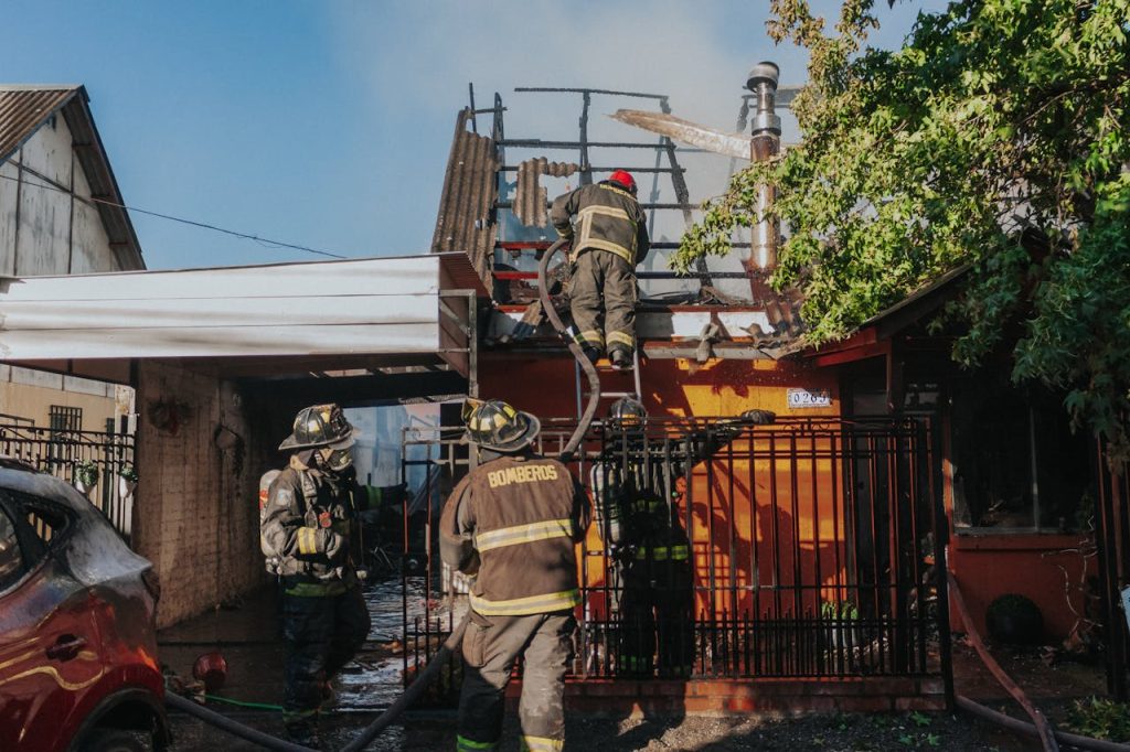 Firefighters working to extinguish a house fire, showcasing bravery and teamwork outdoors.